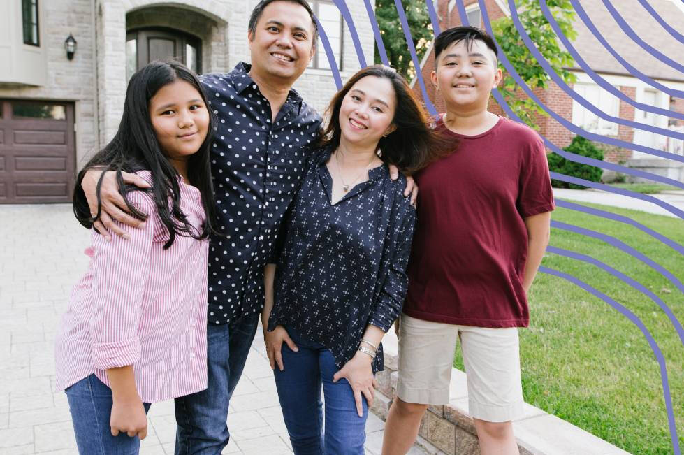 A family of four standing in front of their house
